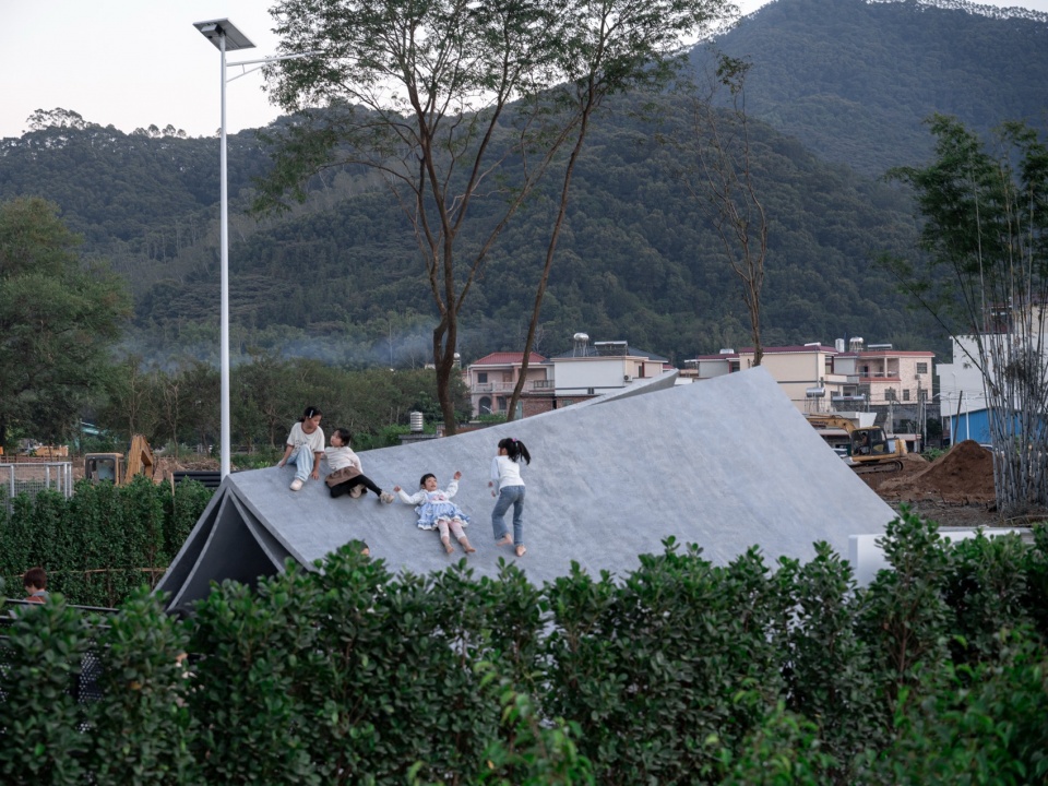 Children climbing on the folded grey plate surfaces of the Pages Afloat public art installation in Huizhou Village of Letters, by f-a-n