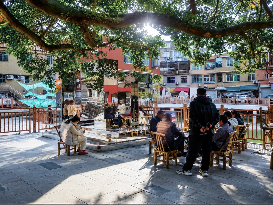 Residents sitting around a mirrored stainless steel public art piece in a Xiamen square