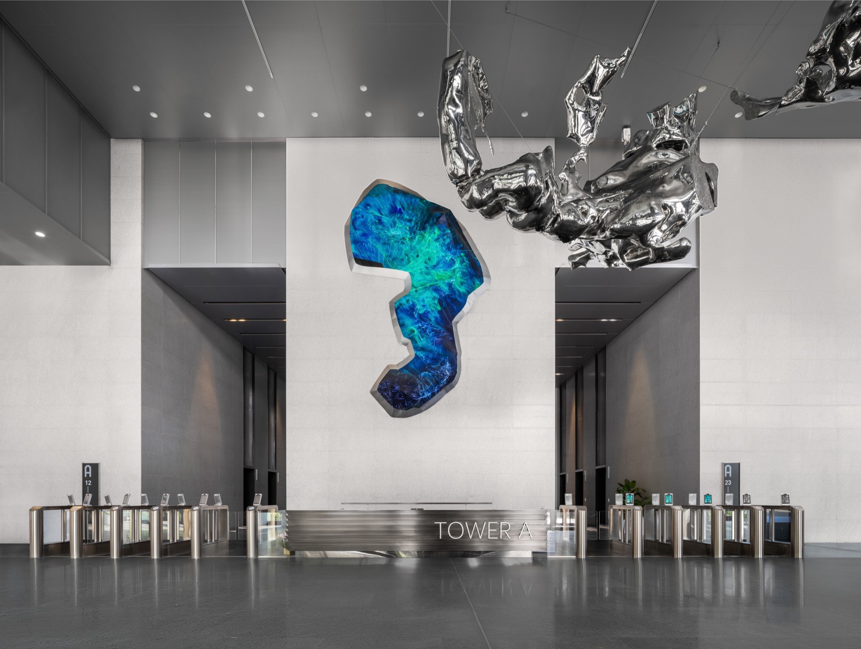 Suspended mirror-polished stainless steel sculpture and illuminated blue wall artwork in the Tower A lobby of Zhaotai International Center, Beijing